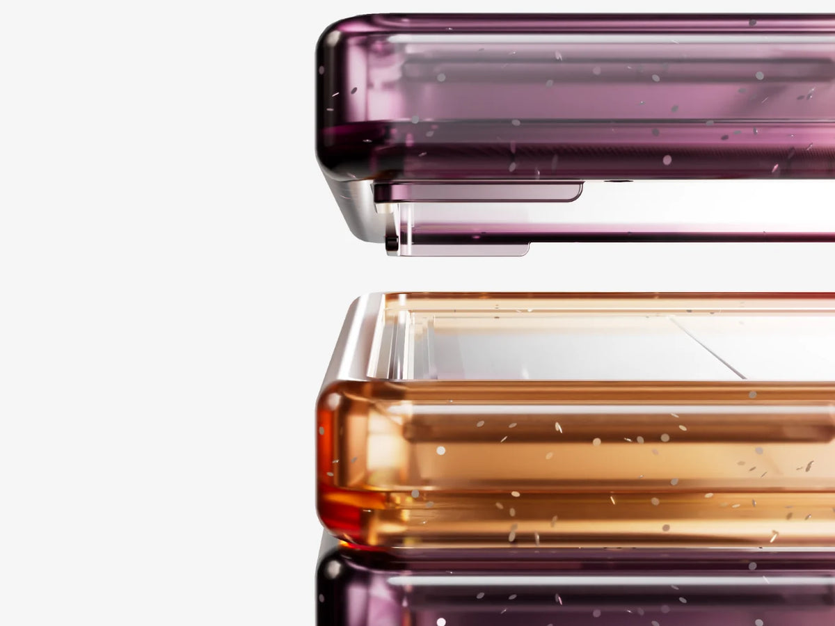 Close-up of stacked Bumpii Aurora graded card guard frames showing translucent magenta, pink and orange corner details.